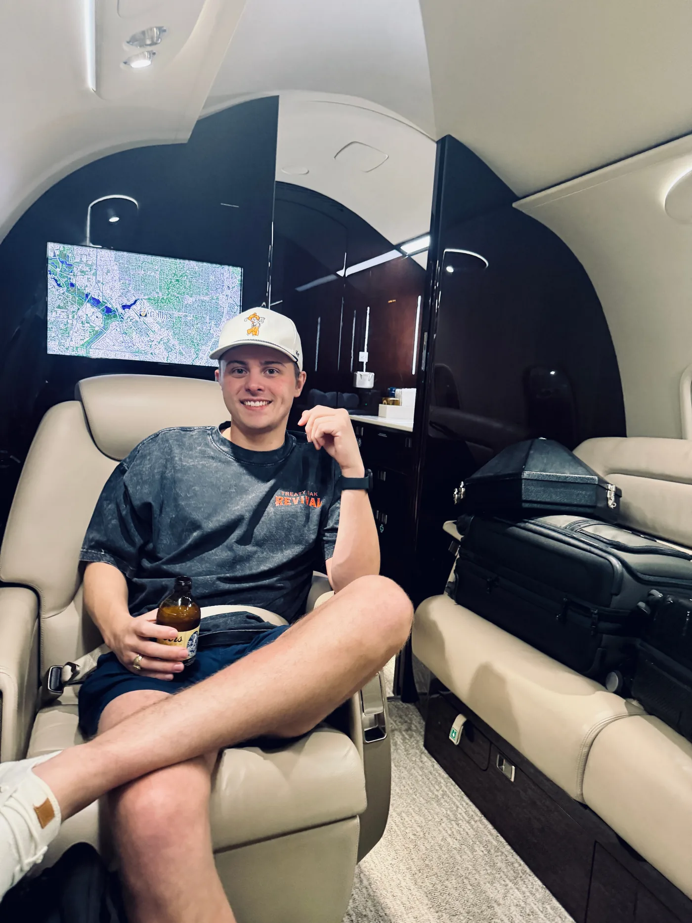 Keaton Hargett seated in a private jet cabin, Dallas on the moving map behind him